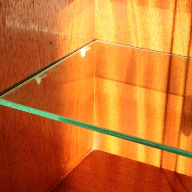 Close-up of vintage teak cabinet interior featuring clear glass shelf and warm wood grain, mid-century Danish design by.