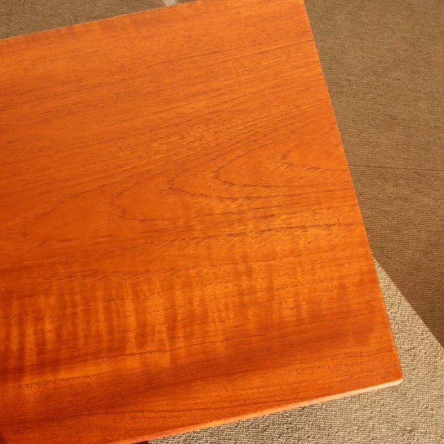 Mid-century vintage teak wood with rich grain and warm tones from British-Denmark design, smooth polished surface.