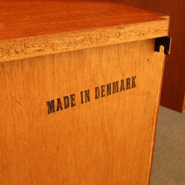 Vintage teak cabinet corner with clear grain, marked "Made in Denmark," showing mid-century craftsmanship.