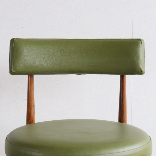 Mid-century British vintage teak dining chair with olive green round cushioned seat and rectangular backrest.