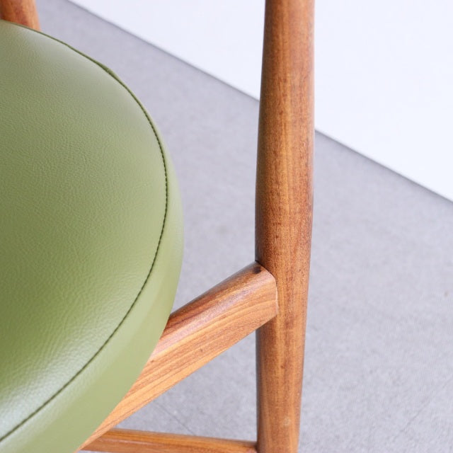 Close-up of vintage British teak dining chair leg and frame, olive-green mid-century upholstered seat with smooth grain and.