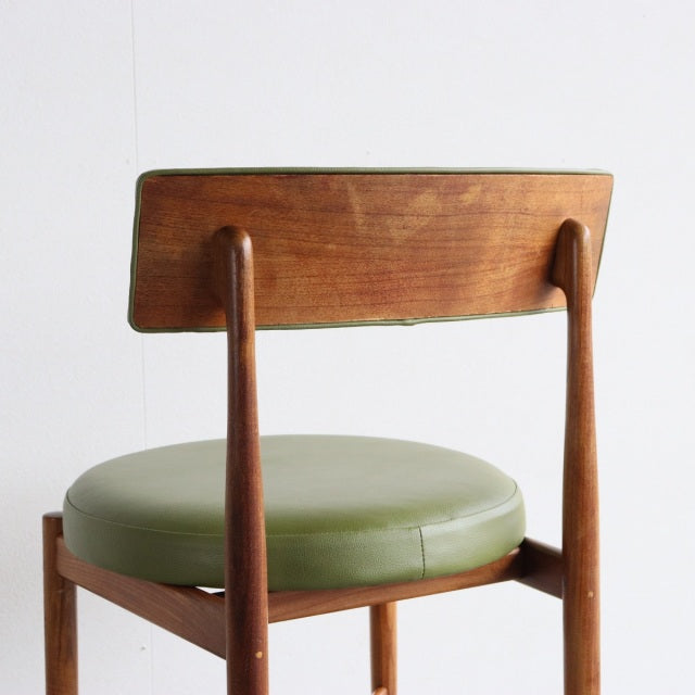Vintage British mid-century teak dining chair with round green leather seat and tapered wooden legs.