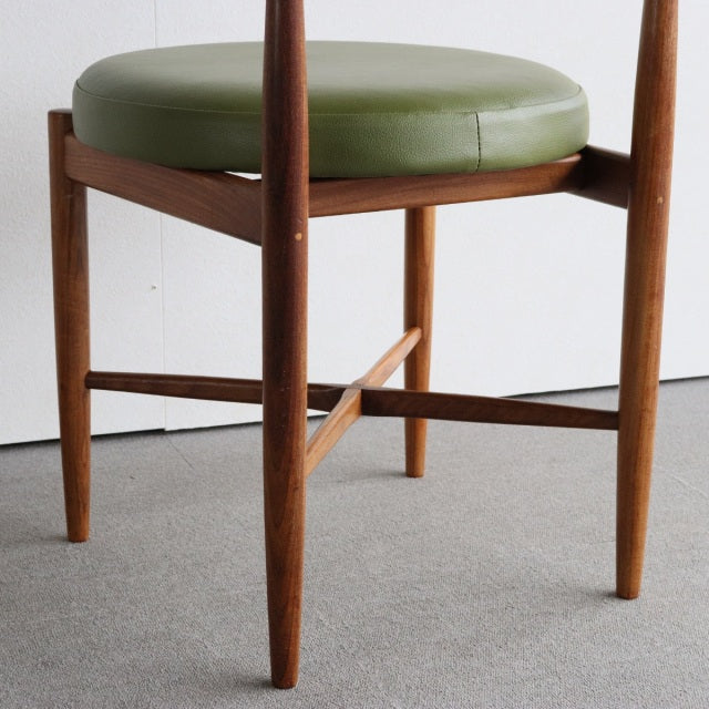 Mid-century British vintage teak dining chair with round olive green leather seat and slender tapered legs.