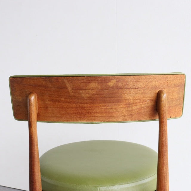 Vintage British mid-century teak dining chair with rounded backrest and green leather seat upholstered, slender tapered legs.