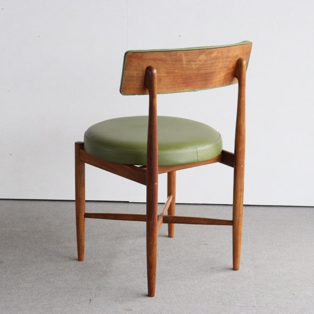 Vintage British mid-century teak dining chair with round green upholstered seat and tapered legs, cross-stretcher support.