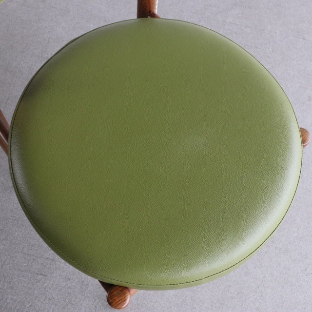 Vintage British mid-century teak dining chair with round olive green upholstered seat and visible wood grain legs.