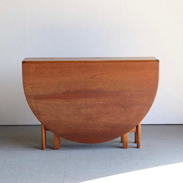 Vintage Jentique mid-century British teak drop-leaf dining table with rich wood grain and slender legs.