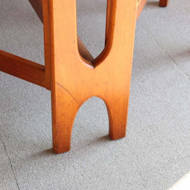 Close-up of mid-century British teak drop-leaf table leg with smooth wood grain and rounded arch design.