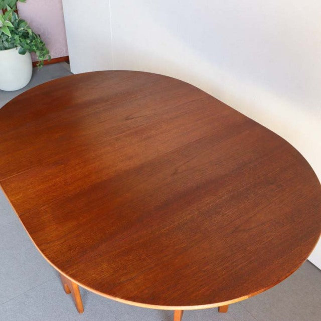 Mid-century vintage British teak drop-leaf dining table with smooth wood grain and rounded edges.
