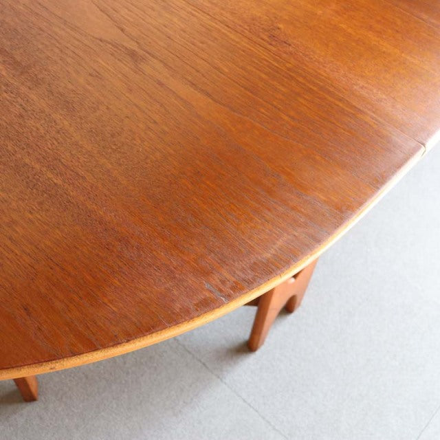 Vintage teak drop-leaf table with smooth grain, rounded edge, and slender mid-century British style legs.