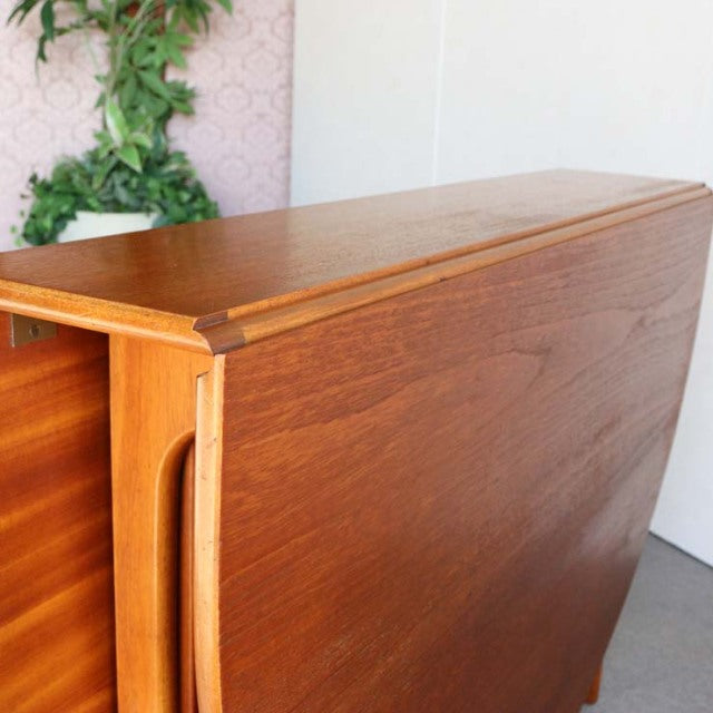 Vintage teak drop-leaf dining table by Jentique, British mid-century design with smooth wood grain and rounded edges.