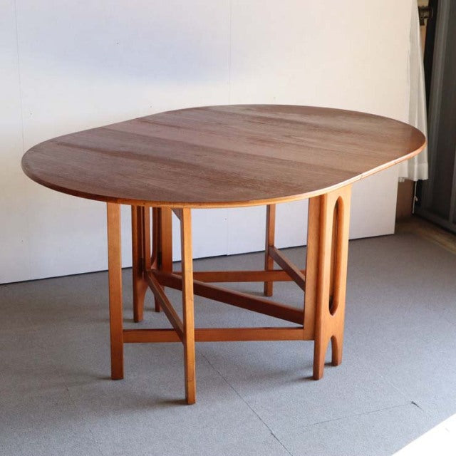 Mid-century British JENTIQUE drop-leaf dining table in warm teak wood with visible grain and sculpted rounded edges.