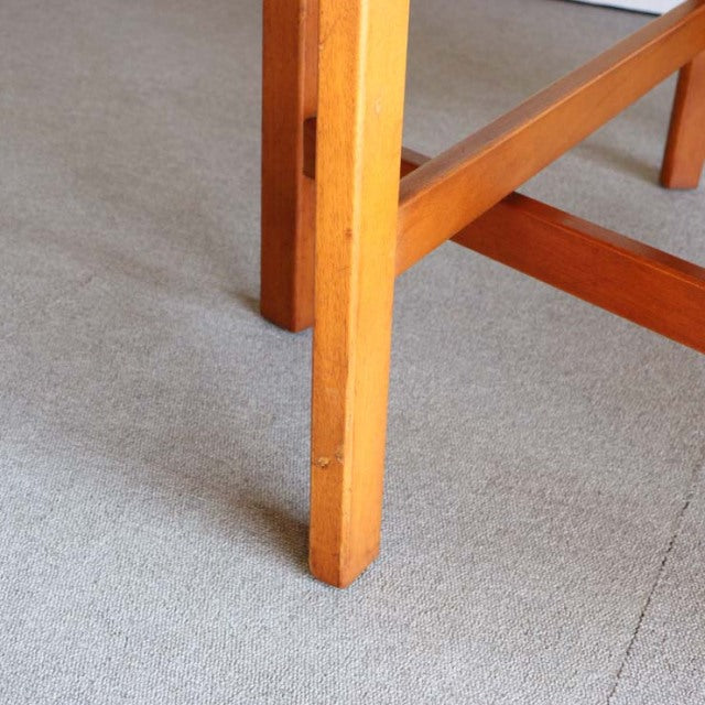 Mid-century British Jentique teak drop-leaf table leg showing warm wood grain and square tapered design on light carpet.