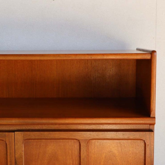 Vintage teak storage cabinet by Nathan with mid-century British-Denmark design, visible wood grain, and sleek rounded edges.