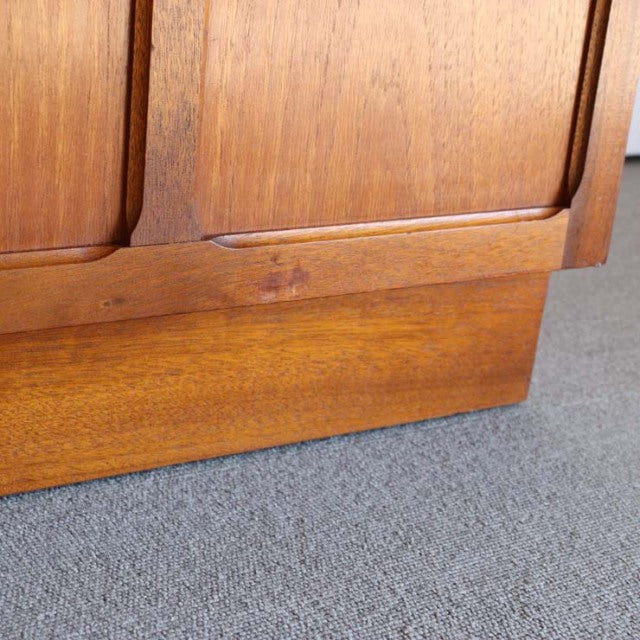 Close-up of vintage teak mid-century British Nathan storage cabinet base with visible wood grain and rounded edge details on .