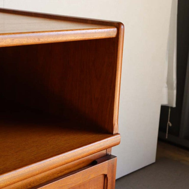 Mid-century British teak storage cabinet by Nathan with smooth wood grain, open shelf, and rounded edges.
