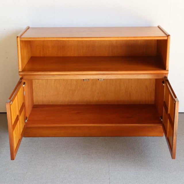 Mid-century British teak cabinet by NATHAN with cross-design doors, rich wood grain, and tapered legs.