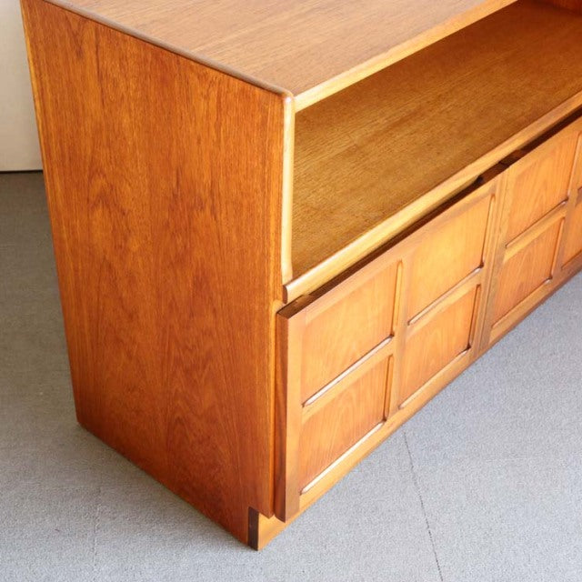 Mid-century British teak cabinet by Nathan with cross-patterned doors and rich wood grain on tapered legs.
