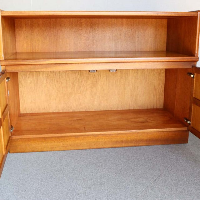 Open mid-century vintage teak storage cabinet by NATHAN with cross design doors, British-Denmark style, visible wood grain,.