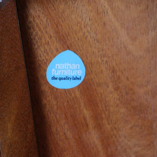 Blue Nathan Furniture quality label on smooth mid-century teak wood grain surface.
