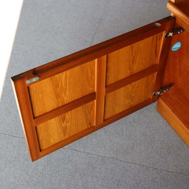 Mid-century Danish teak cabinet door showing rich wood grain and cross design, polished finish.