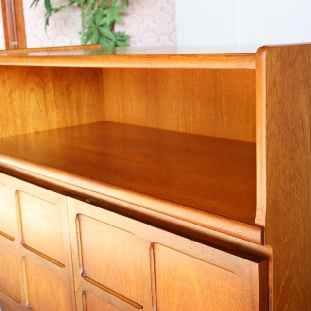 Mid-century British teak storage cabinet by Nathan with cross-design doors and visible wood grain.