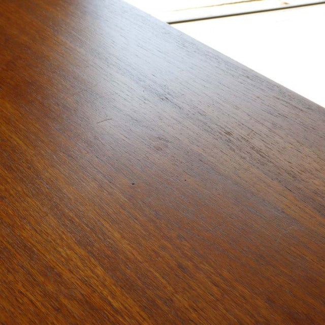 Close-up of vintage mid-century teak wood grain on British Nathan storage cabinet surface showing warm brown tones and.