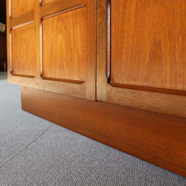 Vintage mid-century teak storage cabinet by Nathan with rich wood grain, cross-panel door design, and Danish-inspired.
