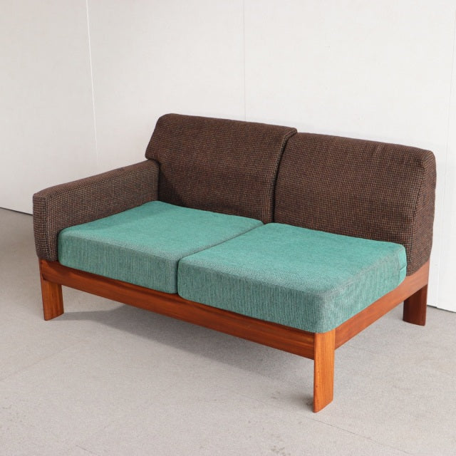 Vintage British mid-century teak two-seater sofa with dark brown backrest and armrests, turquoise seat cushions, and clean.