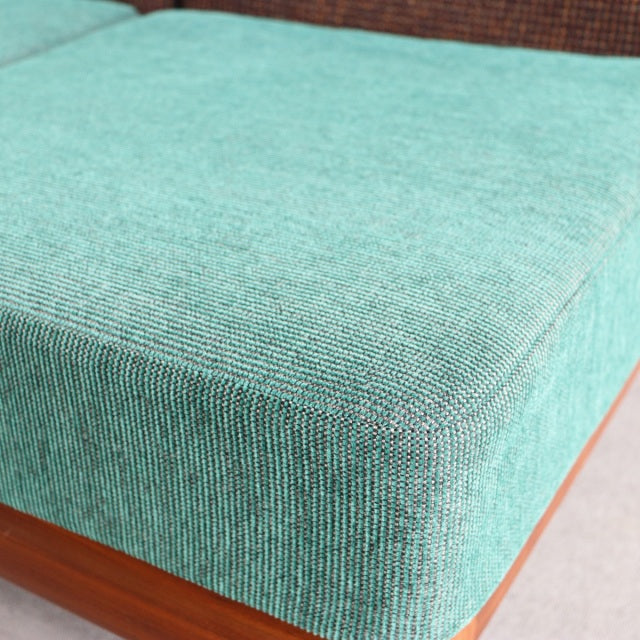 Vintage teak sofa seat cushion with textured light teal fabric, mid-century British-Denmark design, smooth wood grain frame.