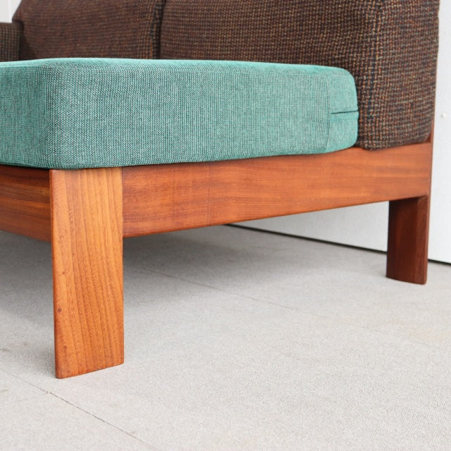 Mid-century vintage British teak sofa leg with rich wood grain, paired with a teal Harris Tweed seat cushion and dark brown.