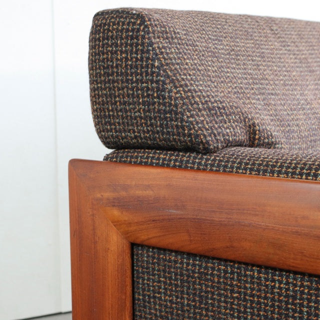 Mid-century vintage British sofa corner with teak frame and textured Harris Tweed upholstery, clean wood grain visible.
