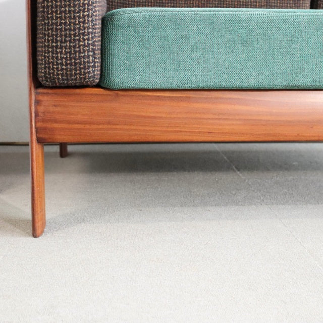 Mid-century vintage British teak sofa leg and frame with rich wood grain and green upholstered seat.