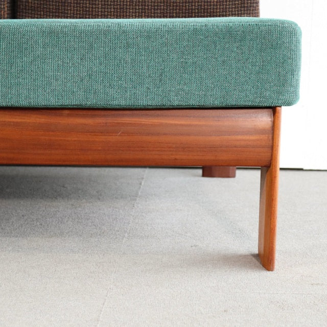 Mid-century vintage British teak sofa leg and frame with visible wood grain, green upholstered seat cushion, clean lines,.