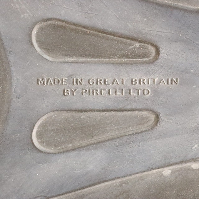 Close-up of embossed "Made in Great Britain by Pirelli Ltd" on vintage British mid-century teak furniture leg with textured.