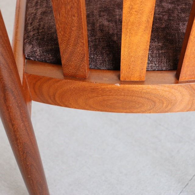 Vintage teak dining chair close-up showing smooth curved backrest with vertical slats and rich wood grain, mid-century.
