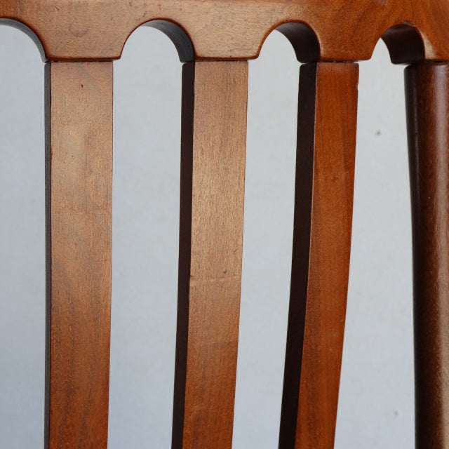 Close-up of vintage teak dining chair backrest with smooth wood grain and curved mid-century British design elements from.