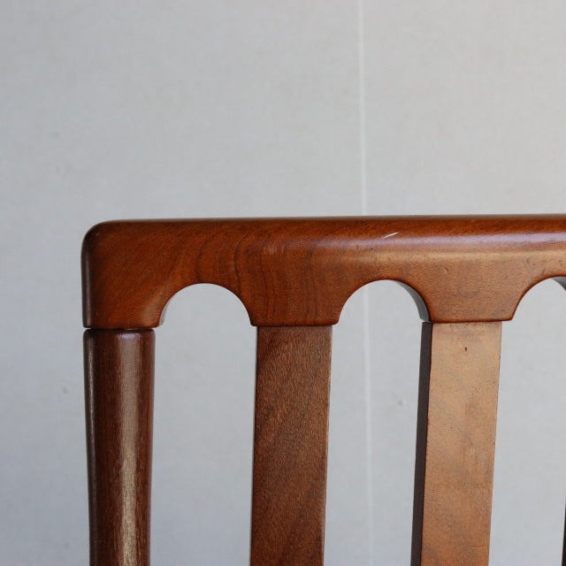 Close-up of Meredew vintage teak dining chair backrest showing warm wood grain, smooth rounded top rail, and vertical slats.