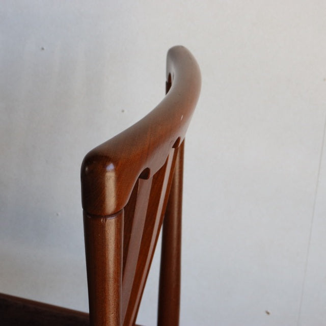 Mid-century British Meredew teak dining chair featuring smooth curved backrest and slender vertical supports, showcasing.