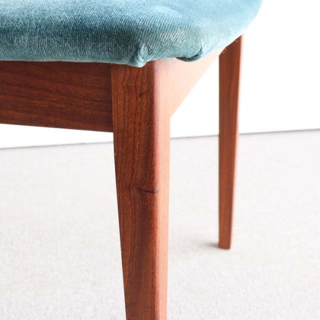Mid-century British G-Plan dining chair with rich teak wood legs and soft blue upholstered seat showing vintage wood grain.