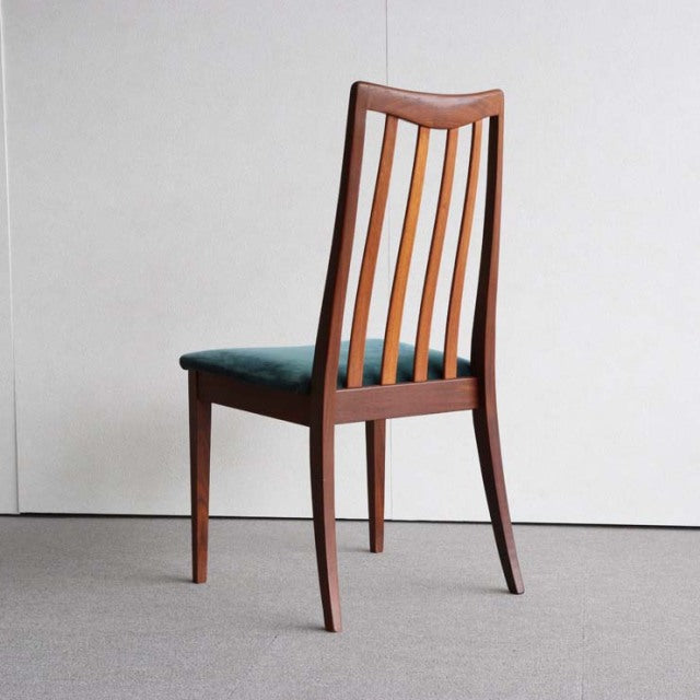 Vintage British mid-century teak dining chair with slender vertical slats and tapered legs, showcasing warm wood grain and.
