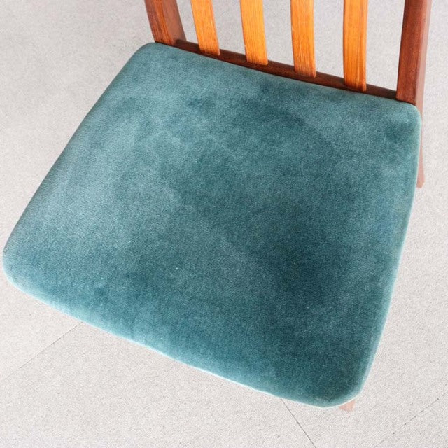 Mid-century British G-PLAN chair with teal velvet seat cushion and teak slatted backrest showing wood grain.