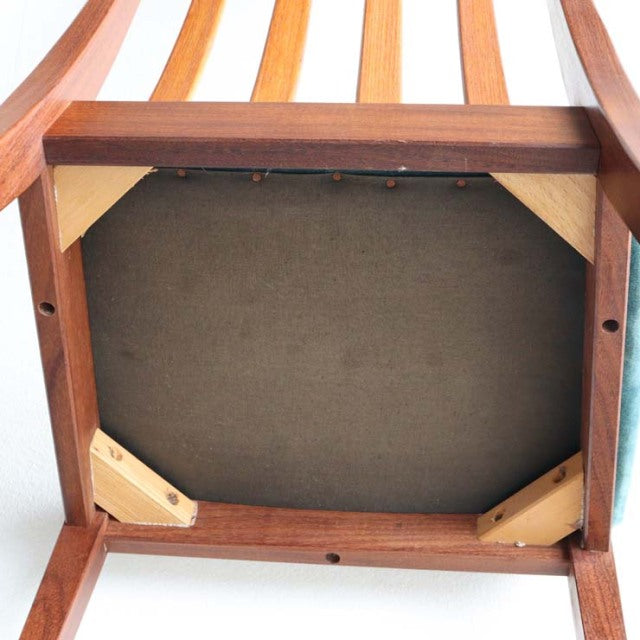Underside of mid-century British G-Plan chair showing teak frame, vintage wood grain, and reinforced corner supports.