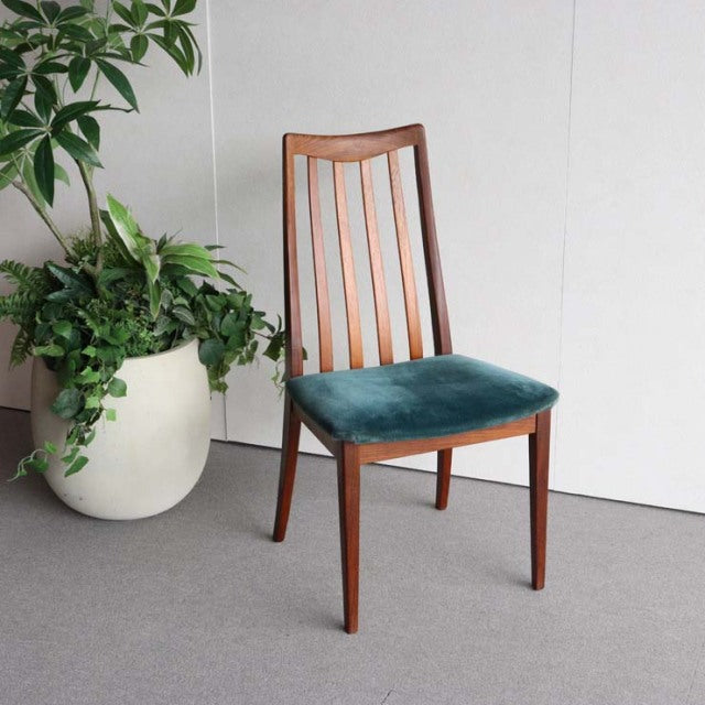 Mid-century British G-Plan teak chair with vertical slatted back and teal velvet seat cushion, vintage wood grain visible.