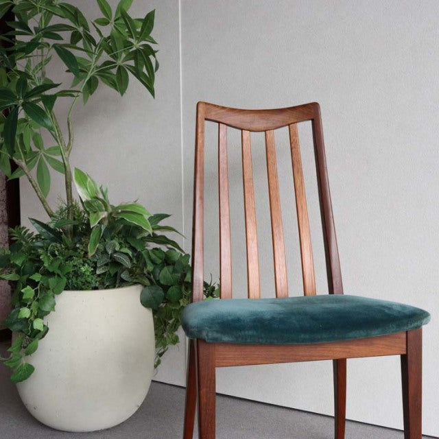 Mid-century British G-Plan dining chair with vintage teak frame and plush green velvet seat cushion, slender tapered legs.