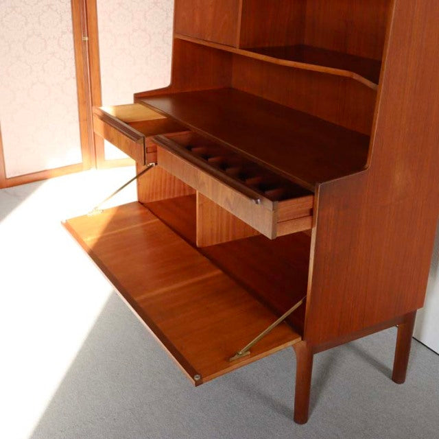 Vintage teak Macintosh mid-century cabinet with open drop-down door and inner drawer, showcasing rich wood grain and slender .