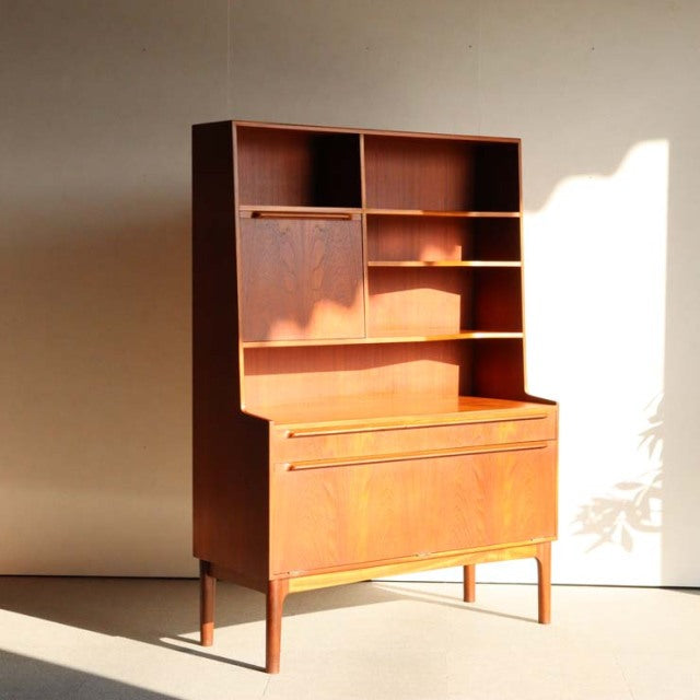 Vintage teak mid-century Macintosh cabinet featuring clean lines, slender legs, open shelves, and smooth wood grain from.
