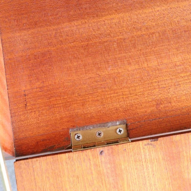 Vintage teak cabinet door close-up showing rich wood grain and brass hinge, mid-century British design by Macintosh.