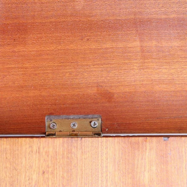 Close-up of vintage British mid-century teak cabinet showing rich wood grain and metal hinge detail.