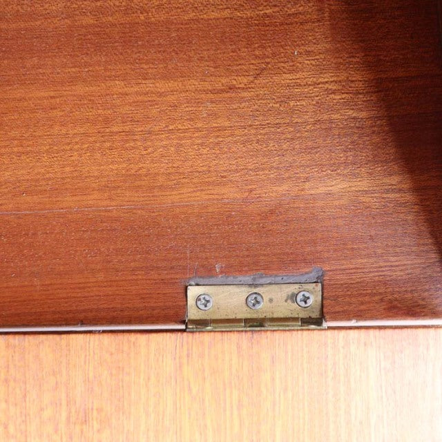 Close-up of brass hinge on vintage teak cabinet door showing rich wood grain and smooth mid-century finish.